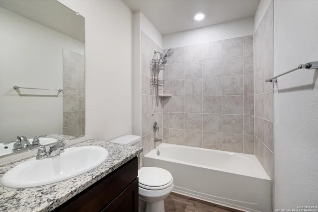 a bathroom with a granite countertop sink a toilet and shower
