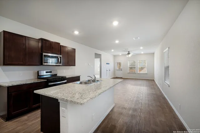 a large kitchen with granite countertop a sink and a stove top oven