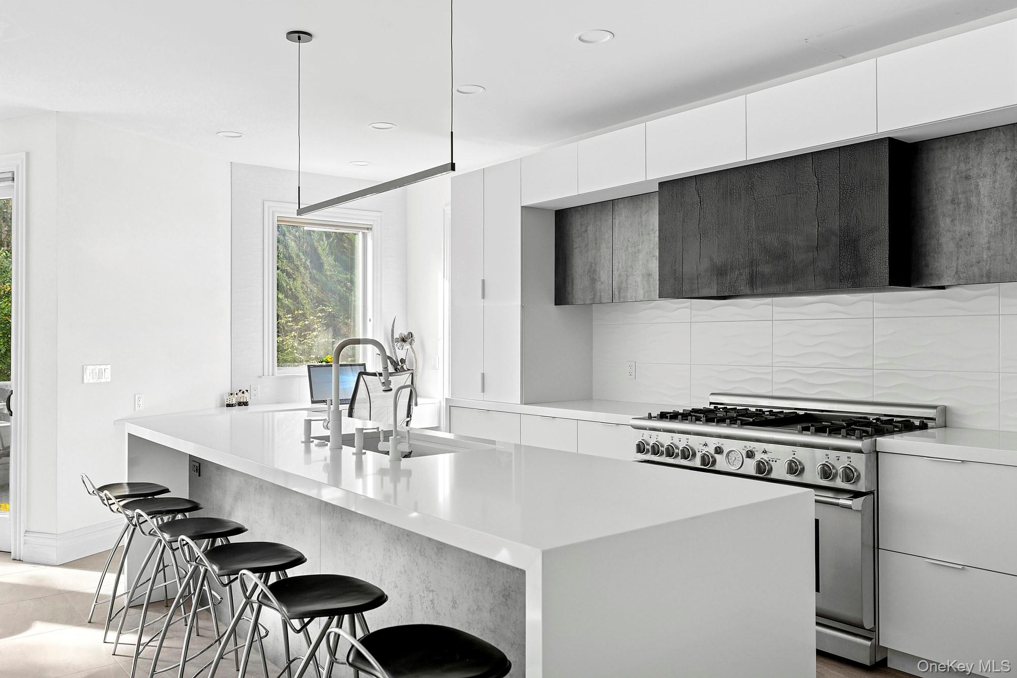 Kitchen with backsplash, stainless steel range with gas cooktop, modern cabinets, a breakfast bar area, and white cabinets