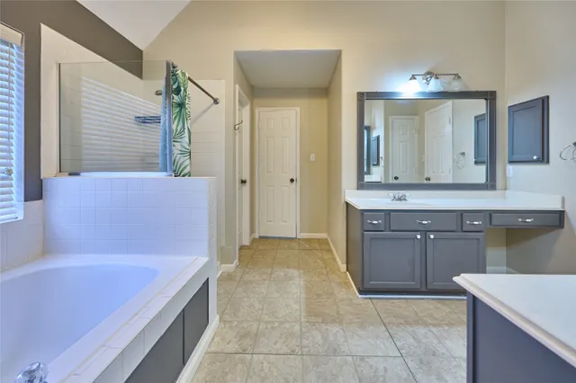 a spacious bathroom with a tub sink and mirror