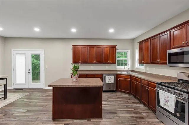 a kitchen with stainless steel appliances granite countertop a stove a sink and a microwave