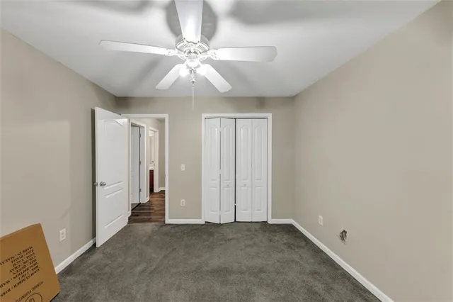 an empty room with chandelier fan and windows
