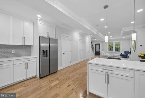a kitchen with kitchen island white cabinets appliances and wooden floor