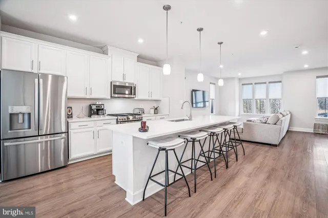 a kitchen with stainless steel appliances granite countertop a stove a sink a refrigerator and a dining table with wooden floor