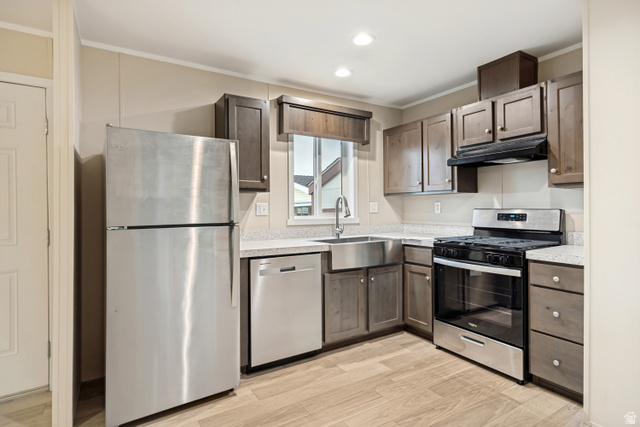 142 Cushing Way Layton, UT 84041 - Photo 5 of 15 Kitchen featuring wood-finish flooring, stainless steel appliances, a farmhouse sink, light-toned countertops, and dark wood cabinetry