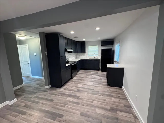 a large kitchen with stainless steel appliances kitchen island granite countertop a refrigerator and a sink