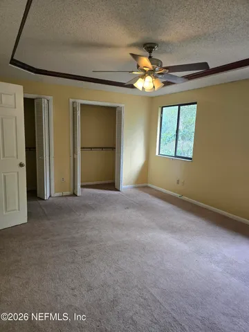 an empty room with a ceiling fan and a window