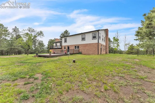 a view of a house with a big yard and large trees