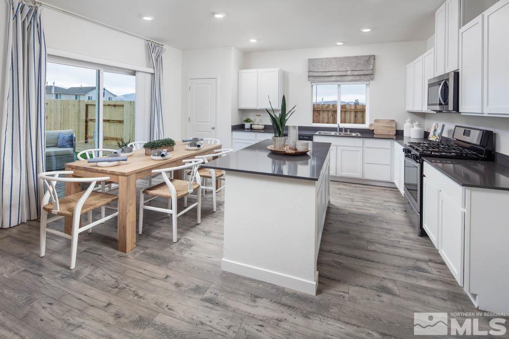 7789 Wandering Way, Unit LOT #243 Reno, NV 89506 - Photo 4 of 15 a kitchen with stainless steel appliances kitchen island granite countertop a table chairs sink and cabinets
