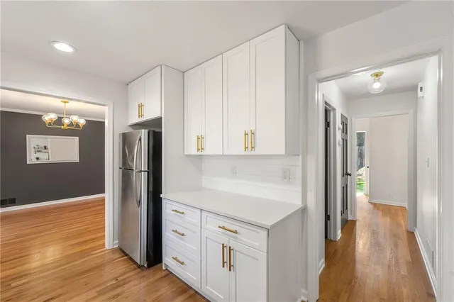 a kitchen with stainless steel appliances a refrigerator and a hard wood floor