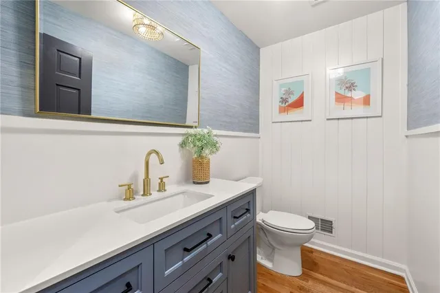 a bathroom with a granite countertop sink mirror vanity and toilet