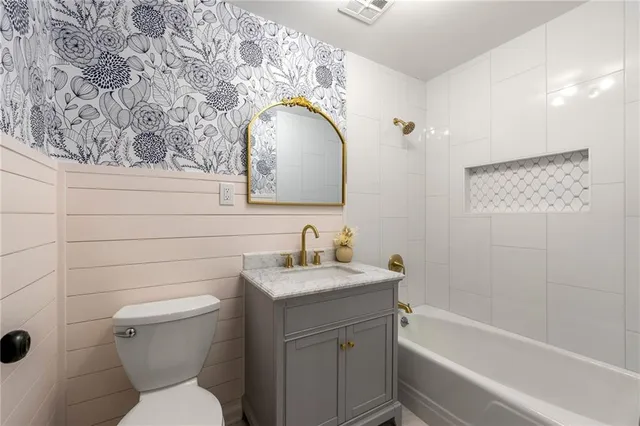 a bathroom with a toilet sink vanity tub and mirror