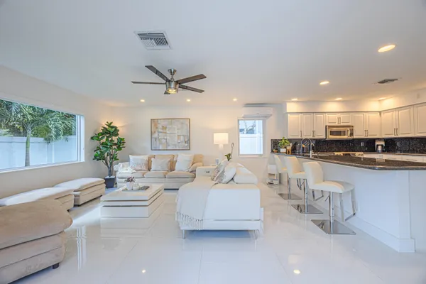 a living room with furniture kitchen view and a large window