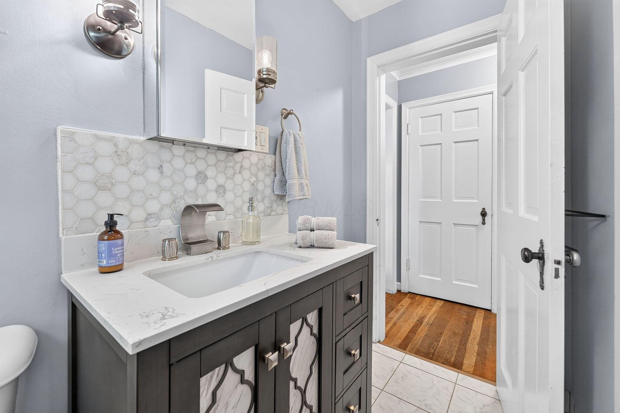 492 Wetmore Road Columbus, OH 43214 - Photo 32 of 55 Bathroom featuring a dark wood vanity with patterned inserts, a white countertop, and a contemporary faucet