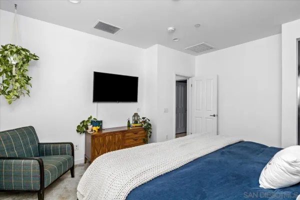 a bedroom with a bed and a flat tv screen on dresser