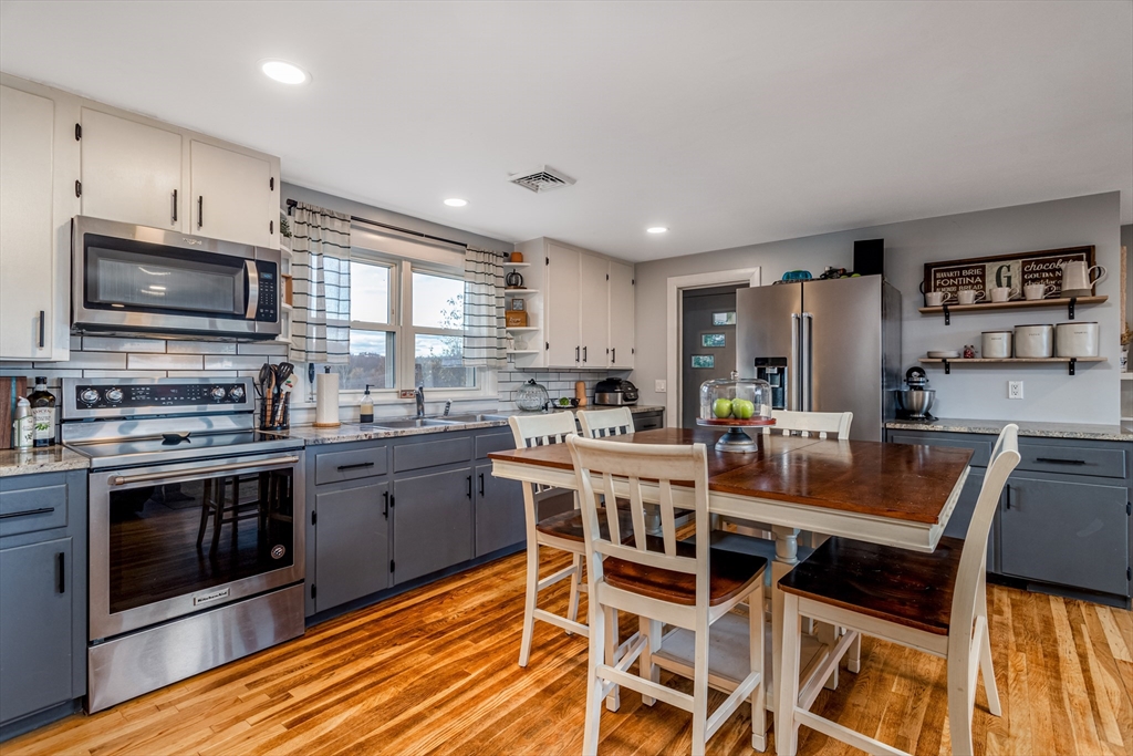319 Chase Road Lunenburg, MA 01462 - Photo 12 of 26 a kitchen with stainless steel appliances granite countertop a stove top oven a sink dishwasher a dining table and chairs with wooden floor
