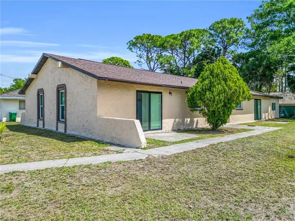 a view of a house with backyard and trees