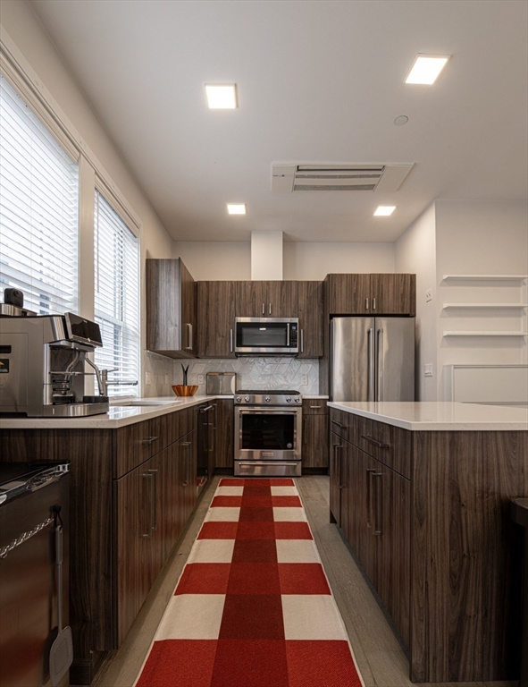 24 Rush Street, Unit I Somerville, MA 02145 - Photo 9 of 21 a large kitchen with stainless steel appliances wooden cabinets a stove and a center island