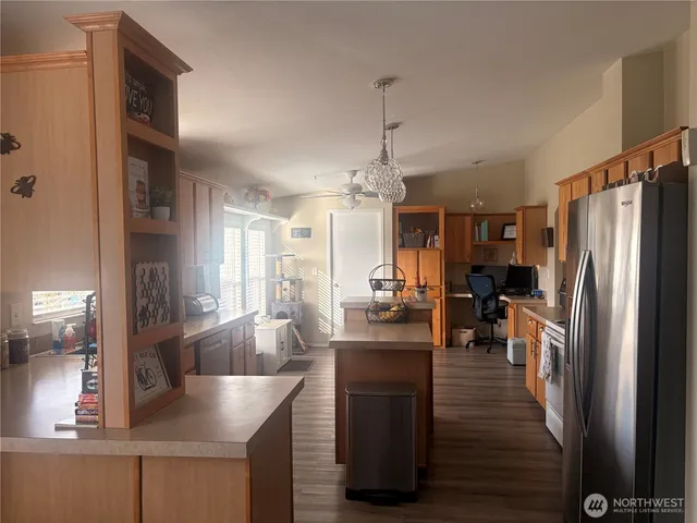 a kitchen with stainless steel appliances granite countertop a refrigerator a sink dishwasher a stove and a dining table with wooden floor