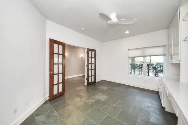 an empty room with windows and ceiling fan