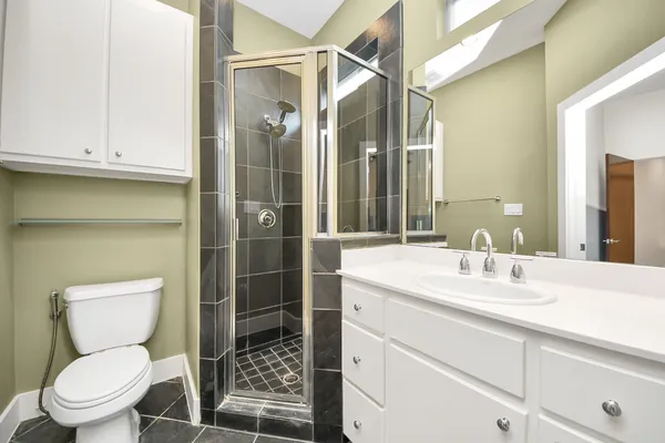 a bathroom with a toilet sink vanity and granite