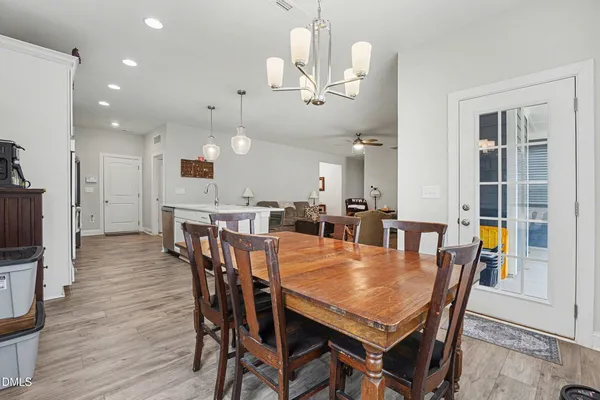 a dining room with wooden floor a chandelier a wooden table and chairs