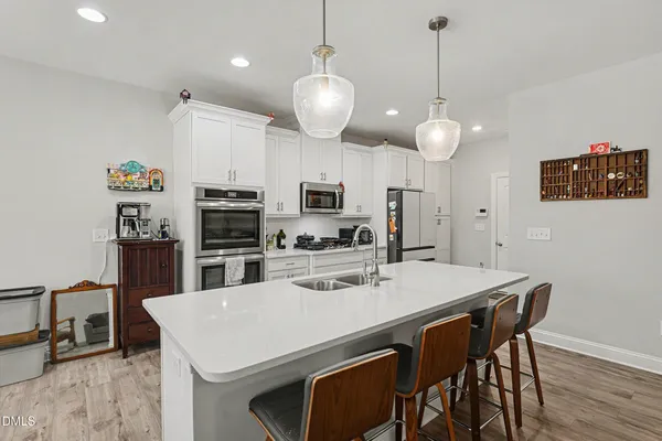 a kitchen with stainless steel appliances a dining table chairs and refrigerator