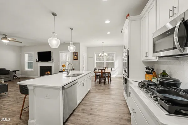 a large kitchen with kitchen island a stove a sink a dining table and chairs with wooden floor