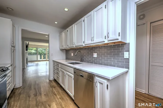 a kitchen with stainless steel appliances granite countertop a sink a stove and a wooden floors
