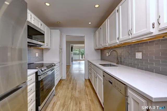 a kitchen with stainless steel appliances granite countertop a stove top oven a sink dishwasher and microwave oven with wooden floor