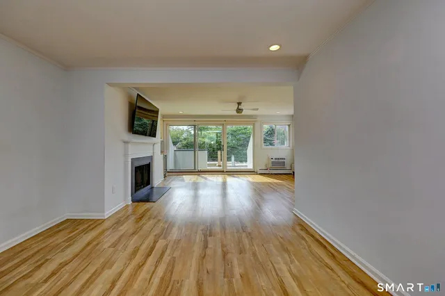 a view of empty room with wooden floor and fireplace