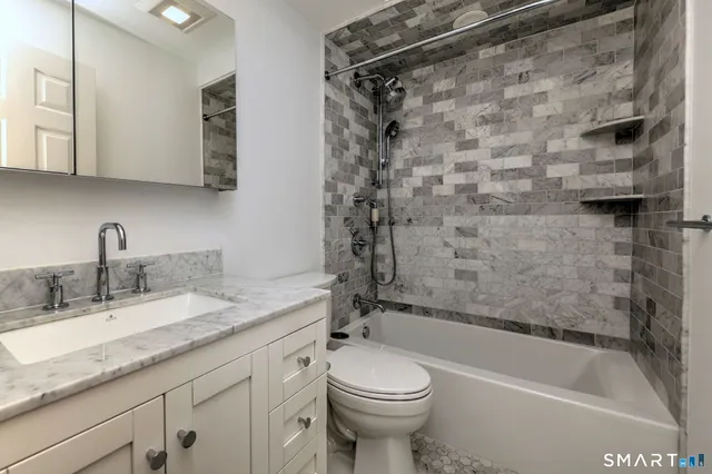 a bathroom with a granite countertop sink toilet and shower