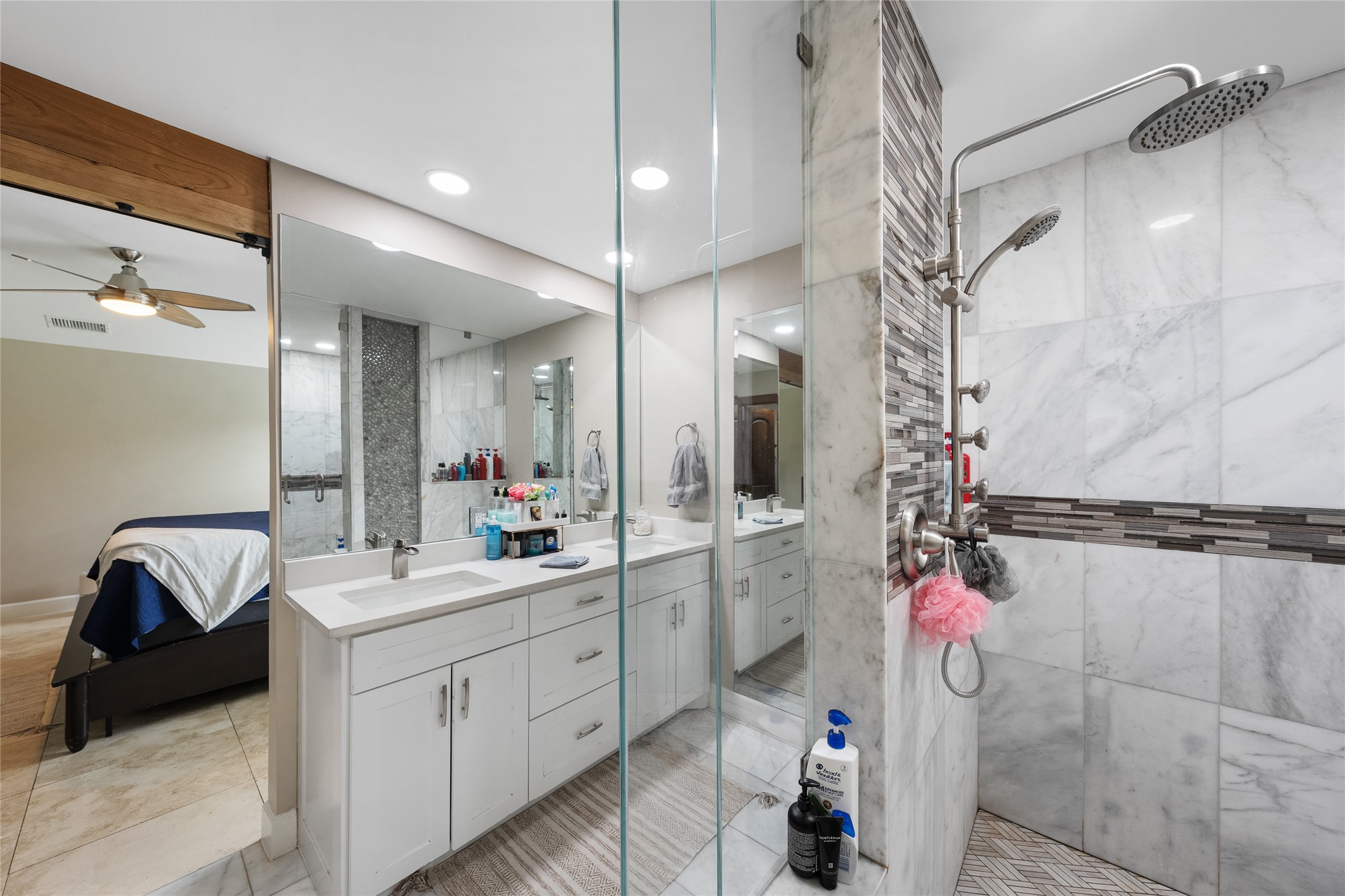 301 Oak Ridge Road Georgetown, TX 78628 - Photo 14 of 34 Spacious bathroom featuring a dual vanity with white cabinetry and undermount sinks, walk-in shower with glass enclosure, rain shower head, and marble-look wall tiling with mosaic accent