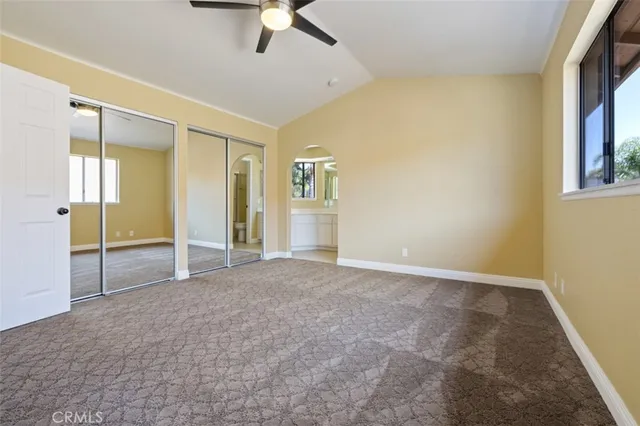 an empty room with chandelier fan and windows