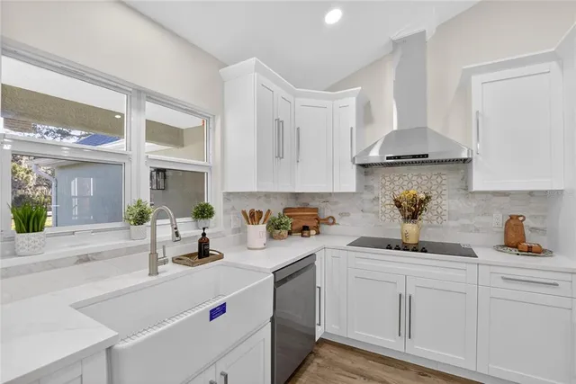 a view of a kitchen with kitchen island a sink dishwasher a refrigerator and white cabinets with wooden floor