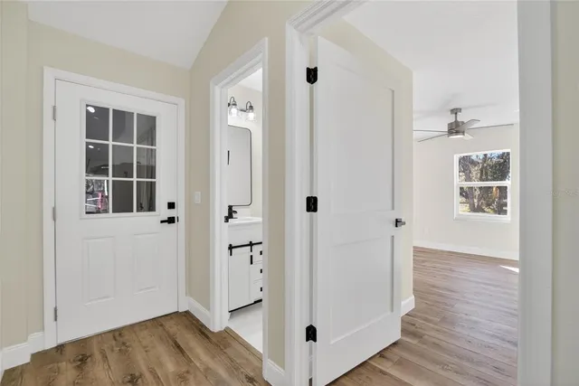 a view of a room with wooden floor a ceiling fan and windows