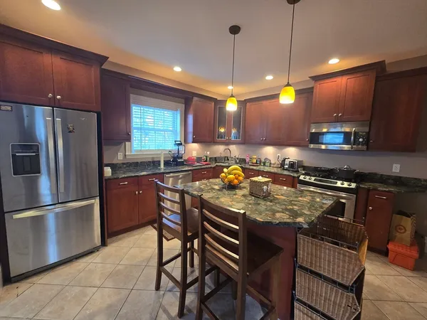 a kitchen with stainless steel appliances granite countertop a refrigerator a stove a sink a dining table and chairs