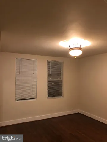 a view of an empty room with wooden floor and a fan