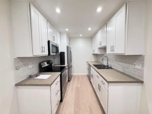 a kitchen with a sink a stove a microwave a refrigerator a sink and cabinets