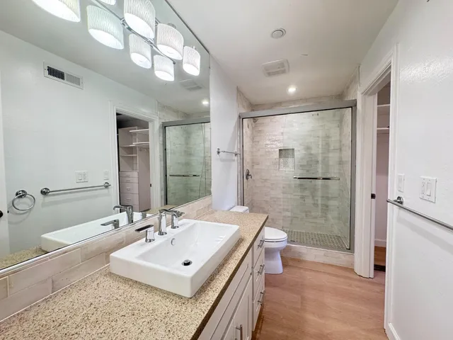 a bathroom with a sink a toilet a mirror and shower