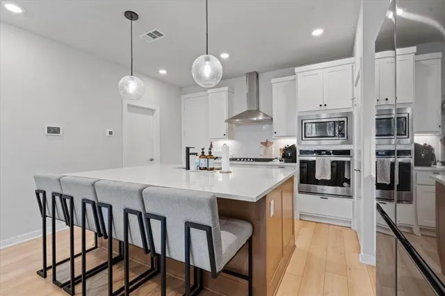 a kitchen with stainless steel appliances granite countertop a sink a stove a refrigerator and island with wooden floor