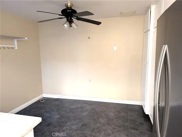 a view of a refrigerator in kitchen and an empty room