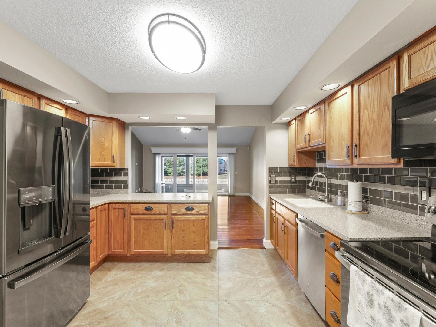 1901 Lakeside Drive, Unit B Champaign, IL 61821 - Photo 9 of 26 a large kitchen with stainless steel appliances granite countertop a stove top oven a sink dishwasher a dining table and chairs with wooden floor