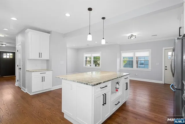 a kitchen with a stove a sink a refrigerator and white cabinets with wooden floor