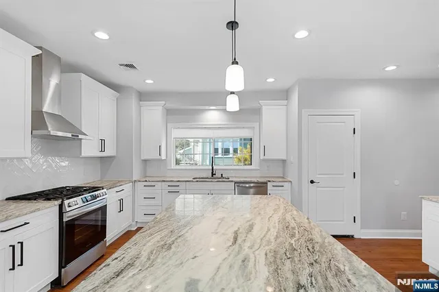 a large kitchen with stainless steel appliances a large counter top a stove and a sink