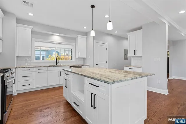 a kitchen that has a lot of white cabinets and wooden floor