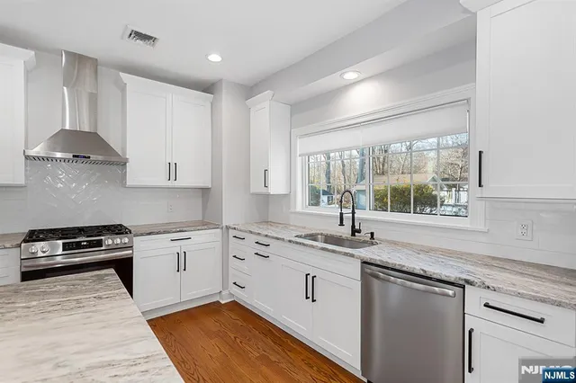 a kitchen with granite countertop stainless steel appliances white cabinets granite counter tops and a window