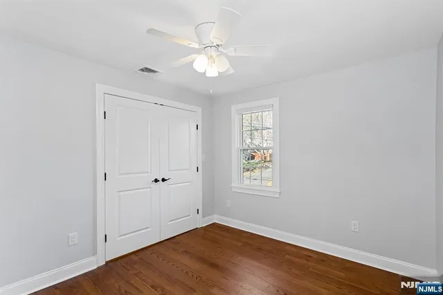 an empty room with wooden floor chandelier fan and windows