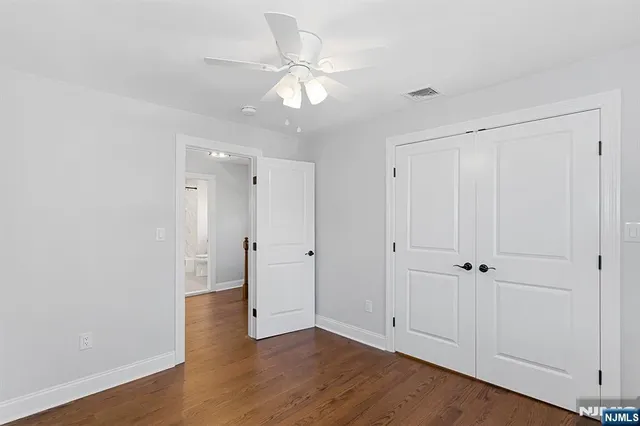 an empty room with wooden floor and ceiling fan