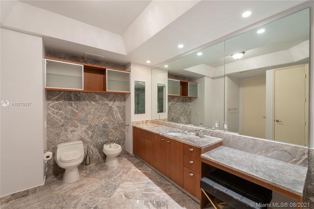 a bathroom with a granite countertop sink a toilet a mirror and bathtub